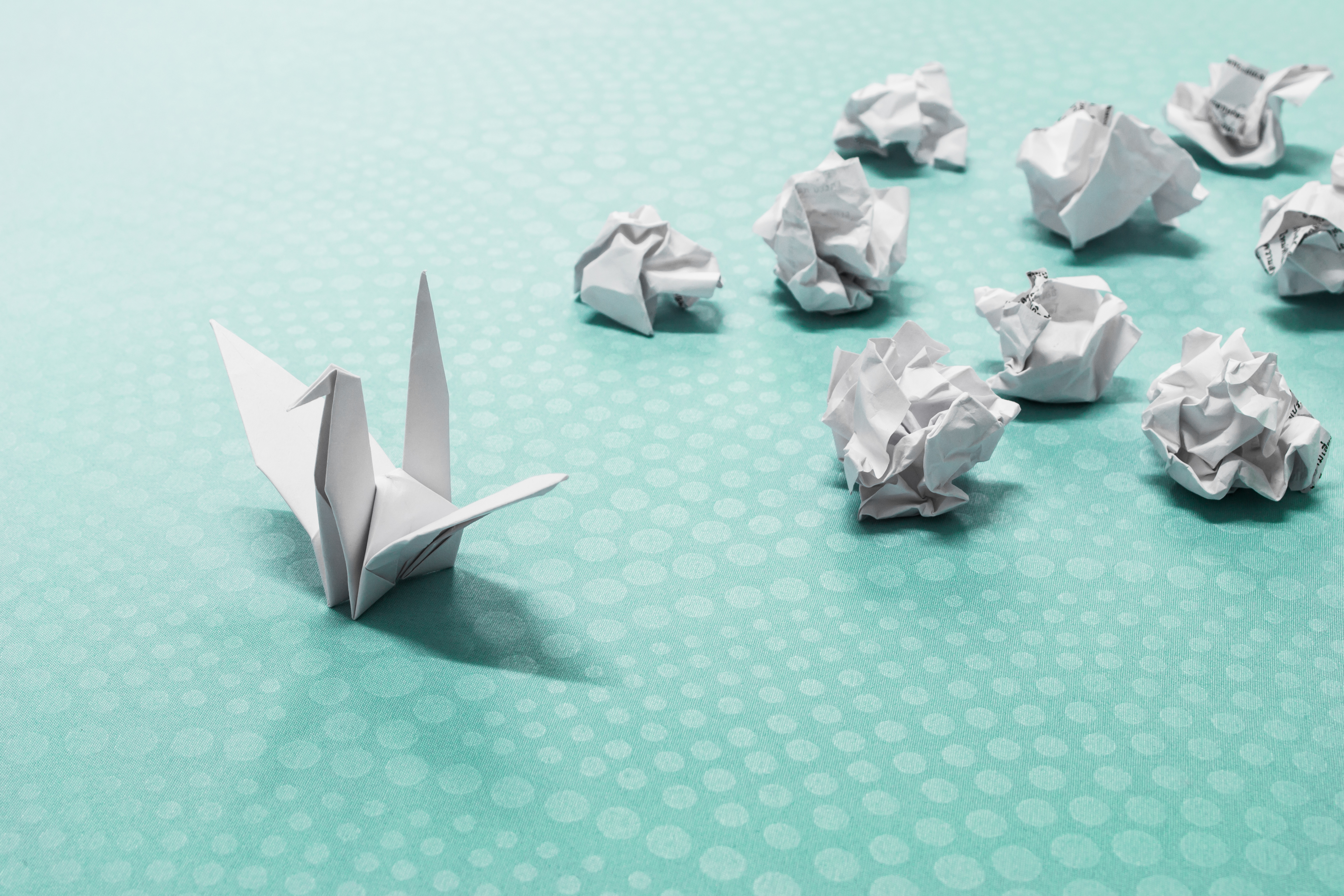 Image of an origami crane and several crumpled pieces of paper to represent success from failure.