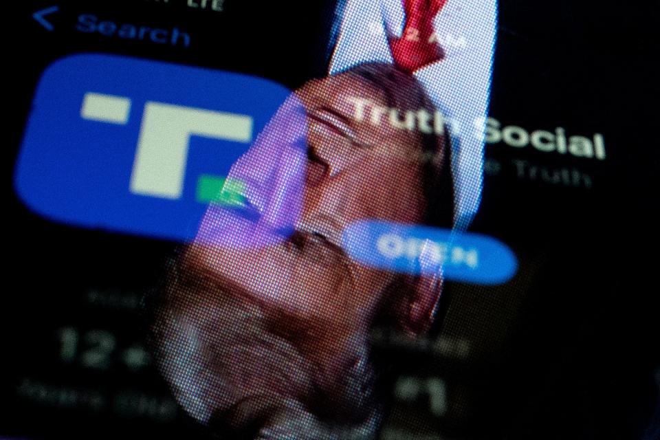This photo illustration shows an image of former President Donald Trump reflected on a phone screen that is displaying the Truth Social app.