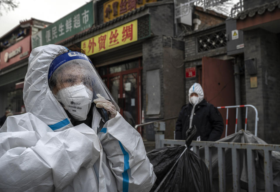 An epidemic control worker wears PPE as her face shield is fogged up in the cold while waiting outside a community in COVID-19 lockdown on December 2, 2022 in Beijing, China. (Photo by Kevin Frayer/Getty Images)